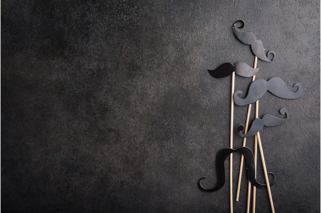 4 moustaches en plastique sont posées sur un fond noir.