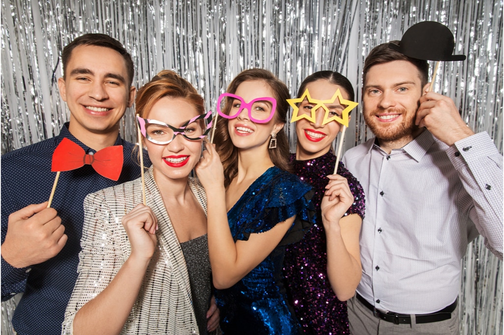 groupe de personnes qui portent des lunettes et accessoires en plastique devant eux lors d'un photobooth