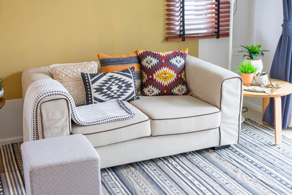Déco ethnique d'une chambre avec un fauteuil blanc et des coussins